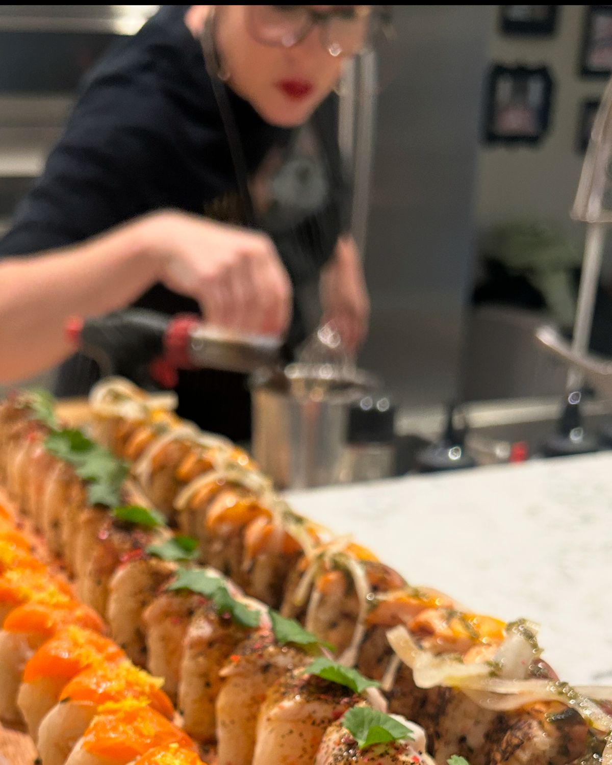 A long tray of nigiri being finished to order in the kitchen